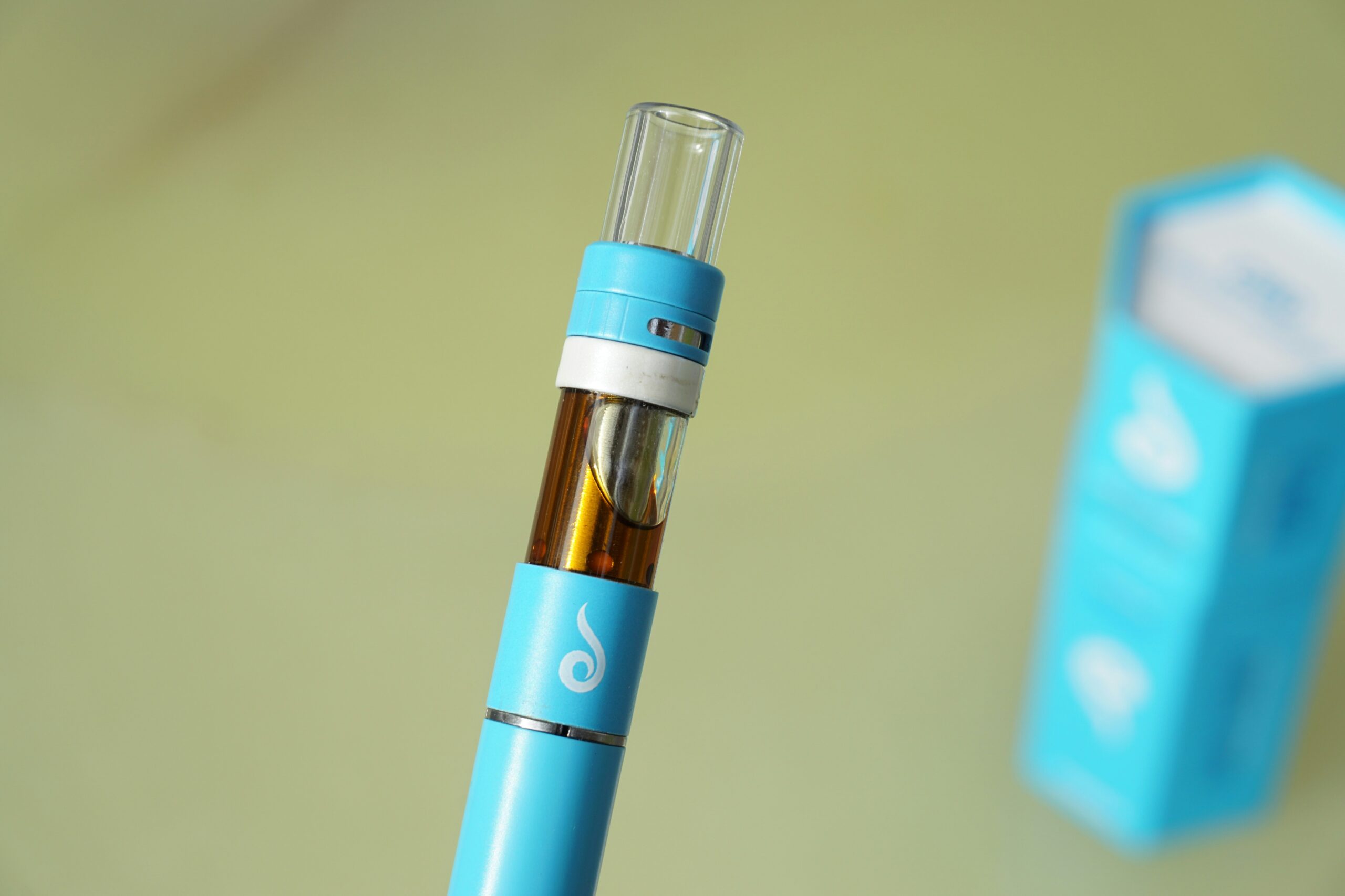Sleek botanical vaporizer battery and ceramic cartridge placed on a wooden surface